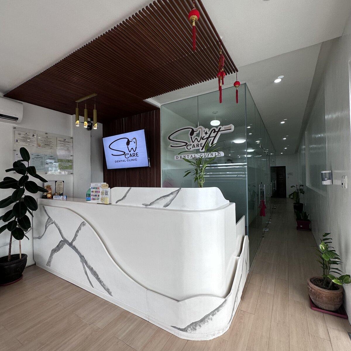 SwiftCare Dental Clinic reception with marble desk and wood-slat ceiling